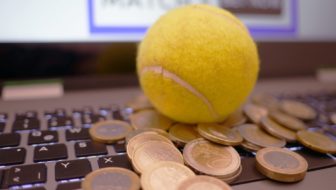 Online Cricket Betting where a ball is placed on the keyboard surrounded by coins.