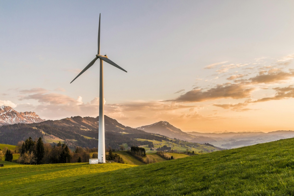 a wind turbine in a green but rocky land during sunset